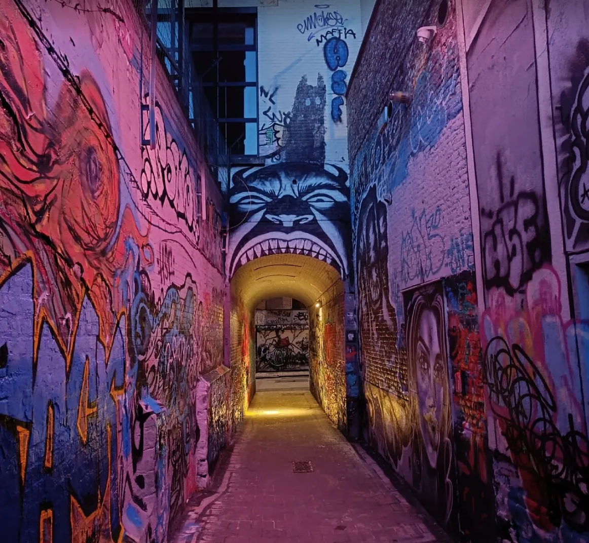 A narrow alley with walls covered in colourful graffiti.