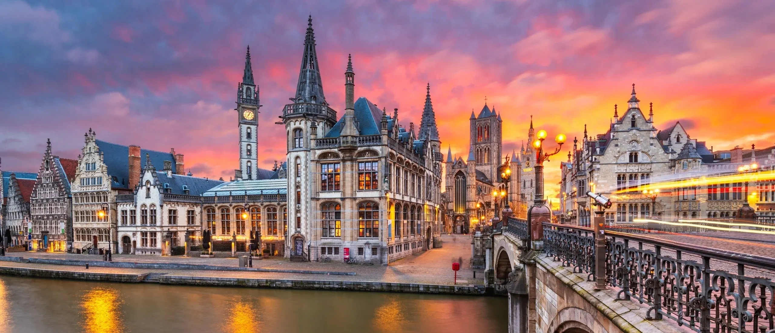 The quays of Ghent at dusk, seen from Saint Michael's Bridge, their lit facades reflected in the water.