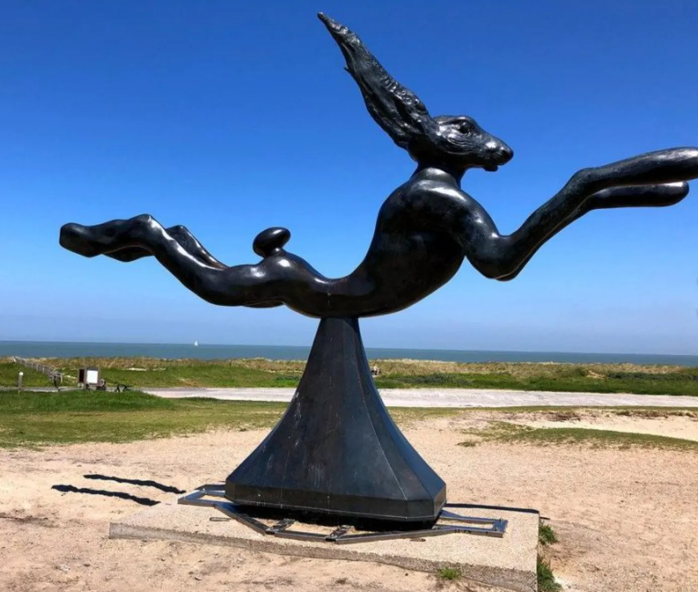 Bronze hare leaping on a pedestal, facing the sea.