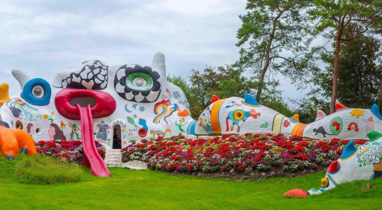 Sculpture of a white and brightly coloured dragon the size of a house.